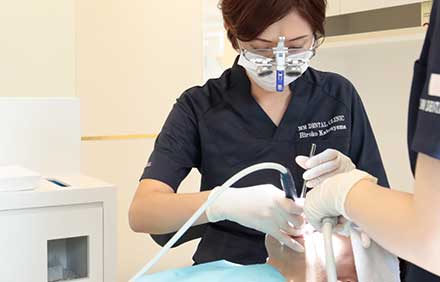 インプラント手術前に歯科治療を行っている女性歯科医師