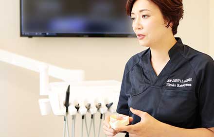 インプラントの模型を手に説明をしてる女性歯科医師