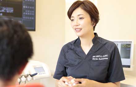 歯の模型を手に持って患者様に説明してる女性歯科医師