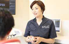 歯の模型を手に持って患者様に説明してる女性歯科医師
