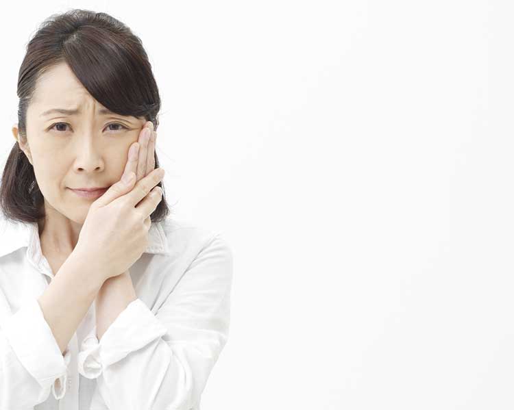 頬に手をあてて歯を痛がっている女性